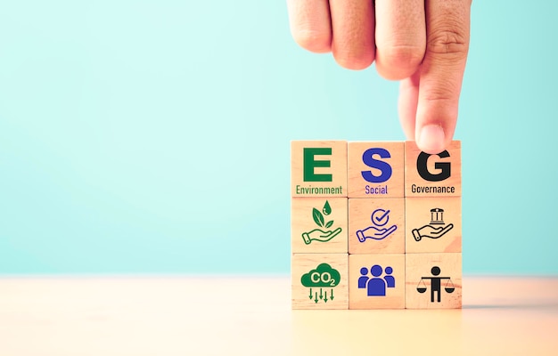 Businessman assemble ESG wording on wooden cube block for sustainable organization development and corporation of Environment Social Governance concept