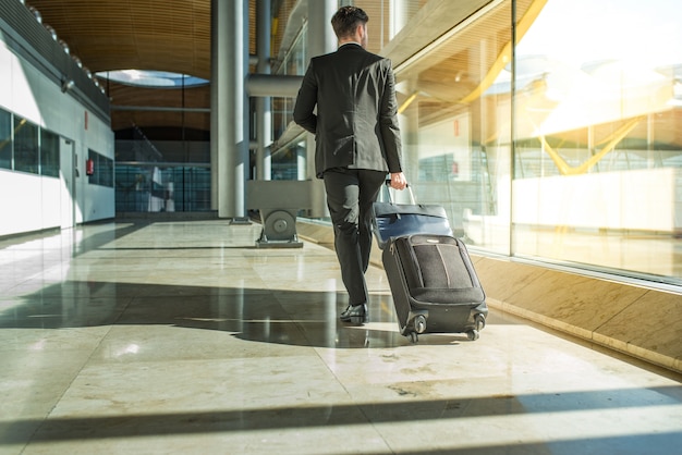 Businessman back and legs walking with luggage at the airport