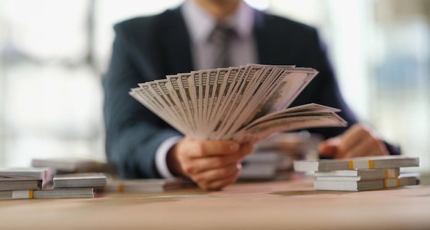 Businessman banker holding fan of dollar bills in hand closeup