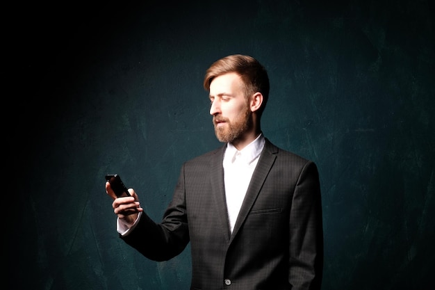 Businessman in black suit talking on the phone on a dark blue background.