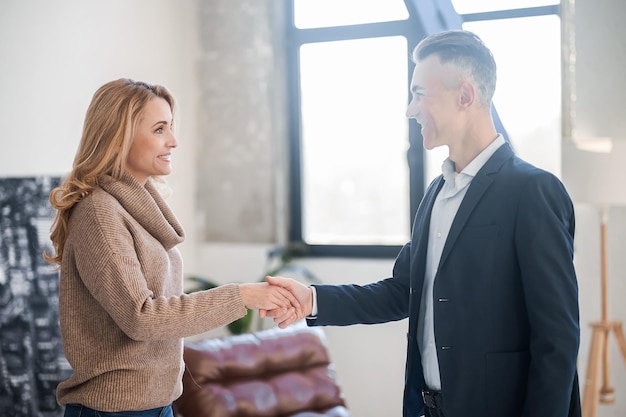 Businessman in a black suit welcoming a female customer