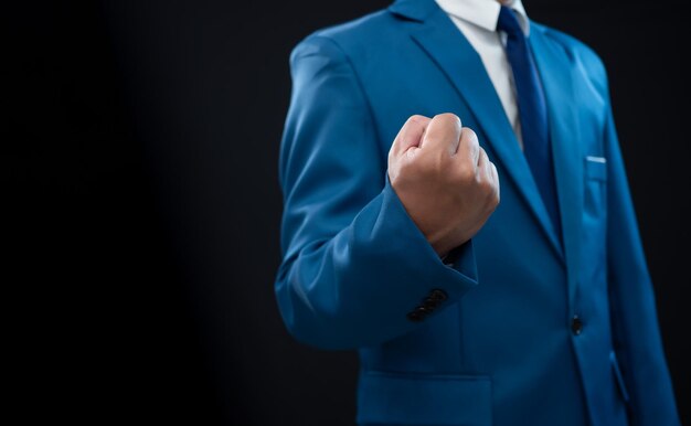 Businessman in blue suit and showing fist on a fresh background