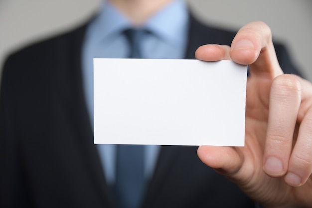 Businessman ,Business Man's hand hold showing business card - close up shot on grey background. Show a blank piece of paper. Paper visit card.