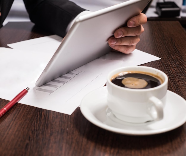 Businessman in business suit uses tablet on the table Cup cafe mobile pen