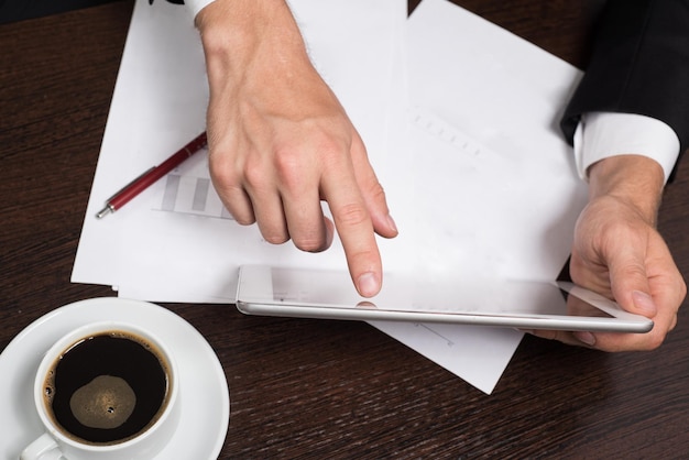 Businessman in business suit uses tablet on the table Cup cafe mobile pen