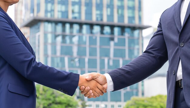 businessman and businesswoman shaking hands in front of corporate building