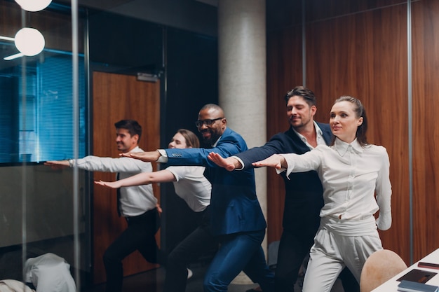 Businessman and businesswoman team doing warm up and yoga exercises before office meeting business h...