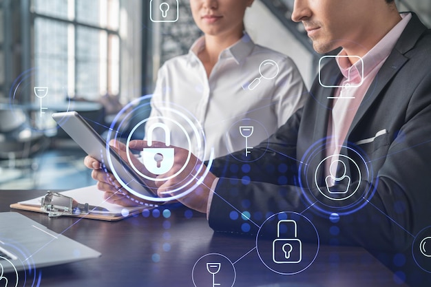 Businessman and businesswoman working together to protect clients confidential information and cyber security IT hologram padlock icons over office background with panoramic windows