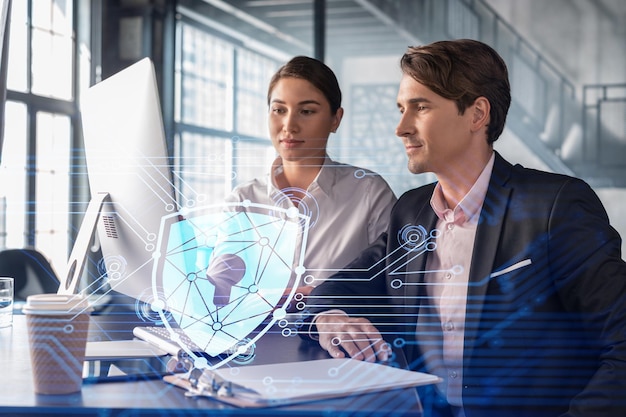 Businessman and businesswoman working together to protect clients confidential information and cyber security IT hologram padlock icons over office background with panoramic windows