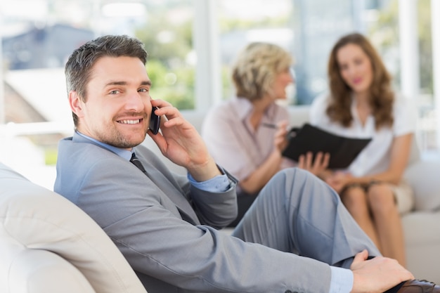 Businessman on call with female colleagues in background