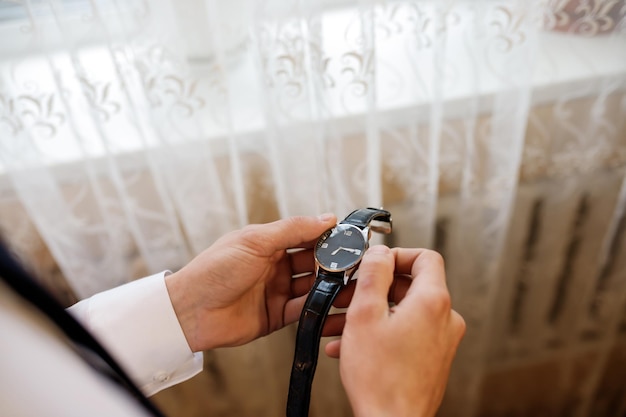 Businessman checking time on his wrist watch man putting clock on hand Groom getting ready in the morning before wedding ceremony Men Fashion