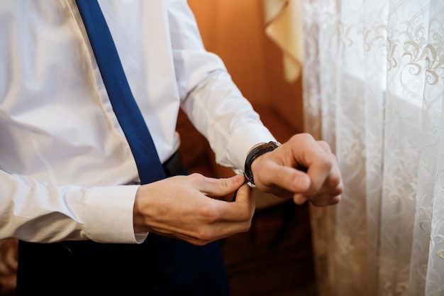 Businessman checking time on his wrist watch man putting clock on hand Groom getting ready in the morning before wedding ceremony Men Fashion