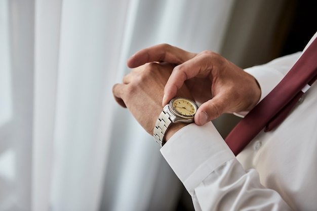 Businessman checking time on his wrist watch, man putting clock on hand,groom getting ready in the morning before wedding ceremony. Men Fashion