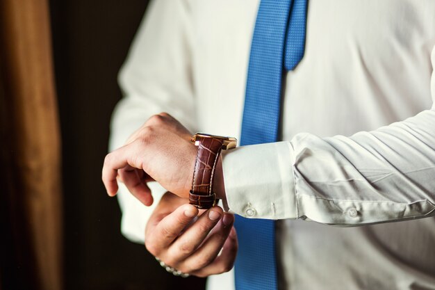 Businessman checking time on his wrist watch, man putting clock on hand,groom getting ready in the morning before wedding ceremony