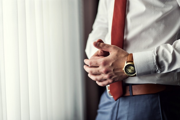 Photo businessman checking time on his wrist watch, man putting clock on hand,groom getting ready in the morning before wedding ceremony