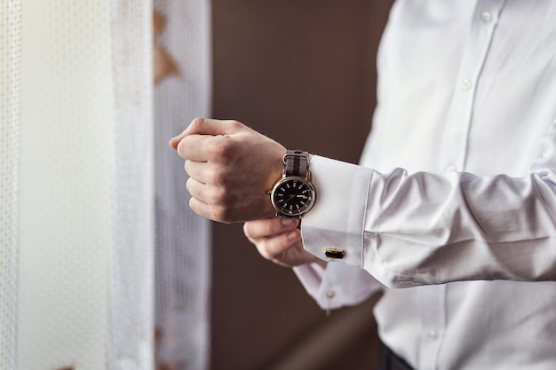 Businessman checking time on his wrist watch man putting clock on handgroom getting ready in the morning before wedding ceremony