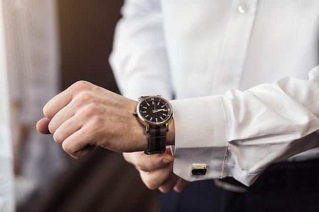 Businessman checking time on his wrist watch man putting clock on handgroom getting ready in the morning before wedding ceremony