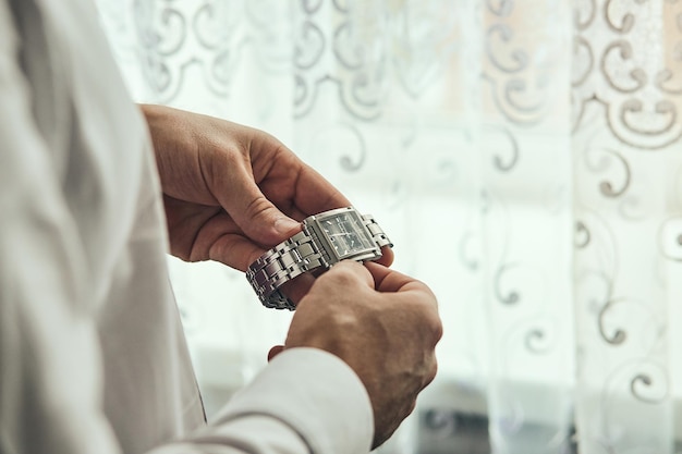 Businessman checking time on his wrist watch man putting clock on handgroom getting ready in the morning before wedding ceremony