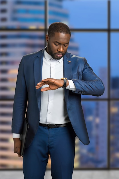 Businessman checking the time on his wrist watch. Young manager is looking on his watch on evening