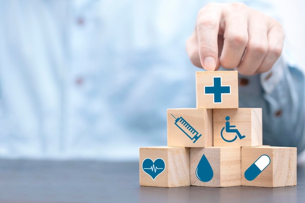 Businessman chooses a emoticon icons healthcare medical symbol on wooden block Healthcare and medical Insurance concept