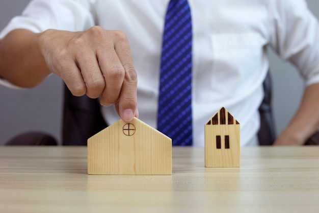 Businessman choosing wood house model and planning to buy property