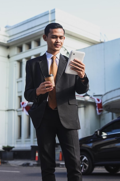 Businessman on the city street with coffee using digital tablet