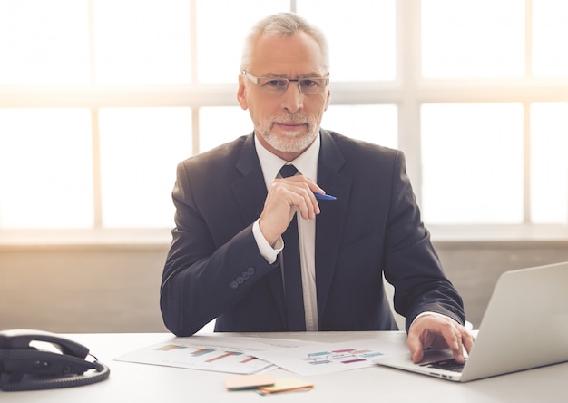 Businessman in classic suit and eyeglasses is using a laptop