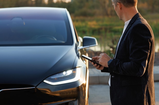 Businessman controls a selfdriving electric car using mobile application autonomous autopilot driver