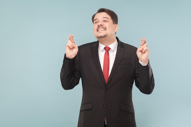 Businessman crosses his fingers and hopes for luck