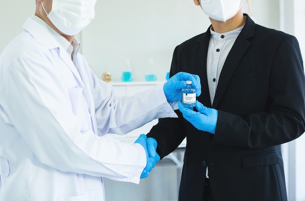 Businessman and doctor shaking hand's for agreement covid19 vaccine in hand.