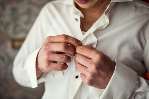 Businessman dresses white shirt, male hands closeup,groom getting ready in the morning before wedding ceremony,