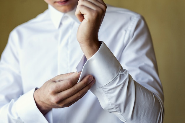 Businessman dresses white shirt, male hands closeup,groom getting ready in the morning before wedding ceremony,