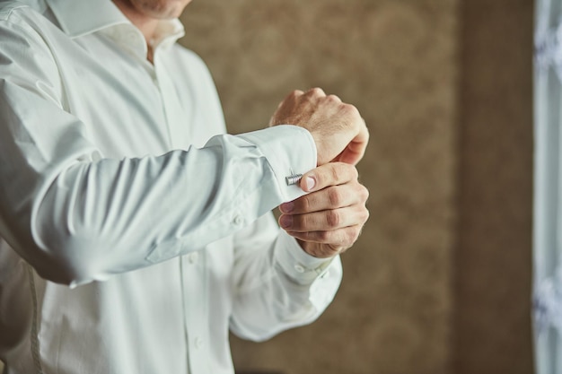 Businessman dresses white shirt male hands closeupgroom getting ready in the morning before wedding ceremony