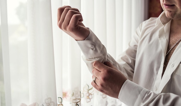 Businessman dresses white shirt male hands closeupgroom getting ready in the morning before wedding ceremony