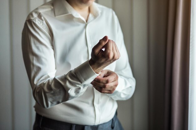 Businessman dresses white shirt male hands closeupgroom getting ready in the morning before wedding ceremony