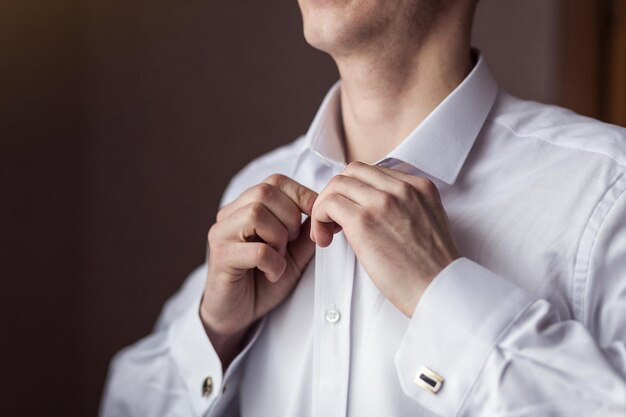 Businessman dresses white shirt male hands closeupgroom getting ready in the morning before wedding ceremony