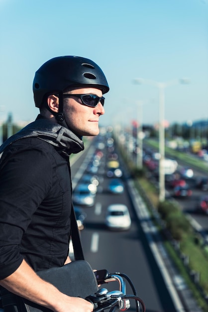 Businessman on electric bicycle standing on bridge