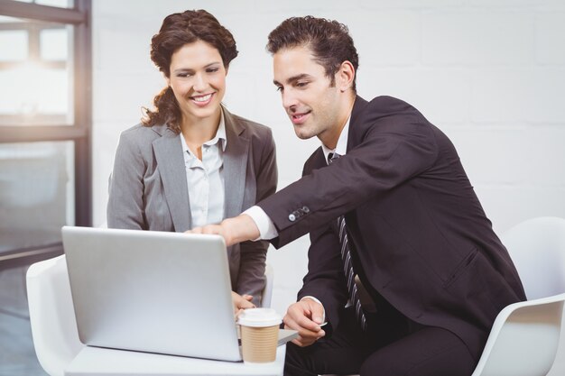 Businessman explaining female colleague over laptop