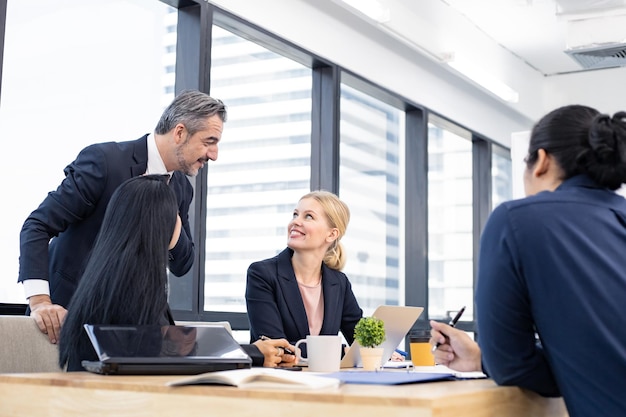 Businessman explaining new business ideas to peers in conference room during meeting at office.