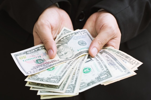 businessman in formal suit hand hold money spread of cash giving money.