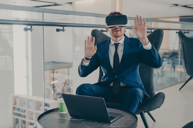 Businessman in formal suit and in VR headset glasses pointing with open palms up in air