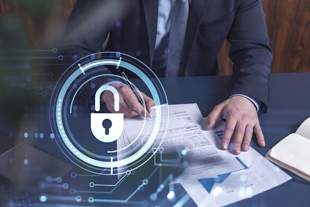 A businessman in formal wear signing the contract to prevent probability of risks in cyber security Padlock Hologram icons over the working desk