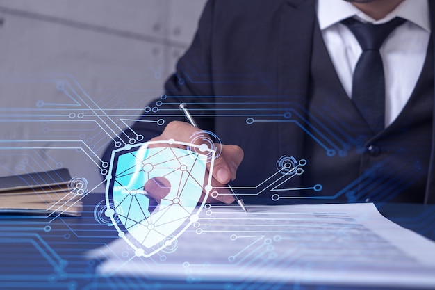 A businessman in formal wear signing the contract to prevent probability of risks in cyber security Padlock Hologram icons over the working desk