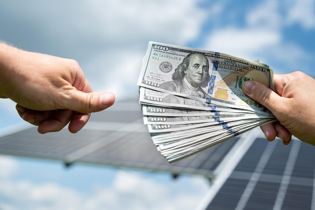 A businessman gives dollars to another person as a deposit after installing solar panels