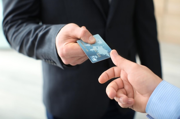 Businessman giving credit card to man closeup