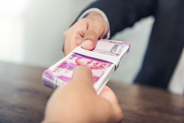 Businessman giving money, Indian rupee currency, to his partner