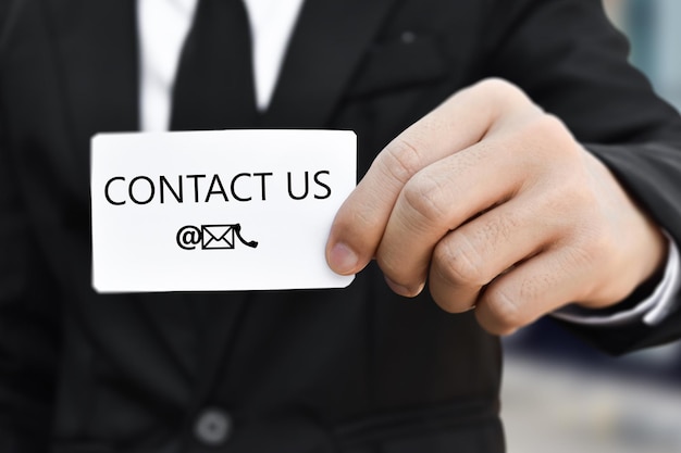 Photo businessman hand holding business card with the message contact us idea for customer support hotline people connect