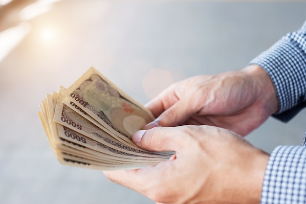 Businessman hand holding Japanese Yen banknote stack. business, money, investment , finance and payment concepts