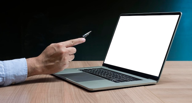 Businessman hand holding pen to display laptop and calculator on table