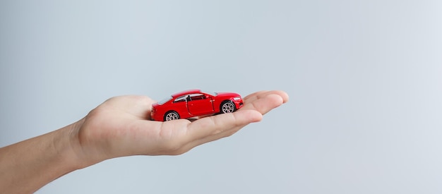 Businessman hand holding red car toy Car insurance warranty rental Financial new and repair concept